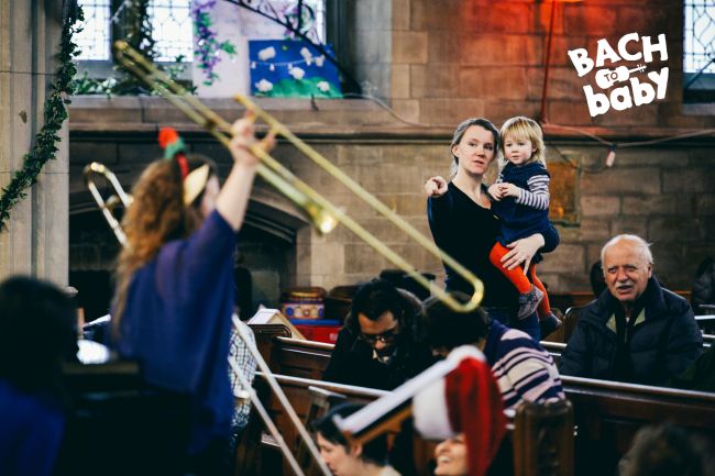 parents and little one watching a trombonist at a bach to baby concert